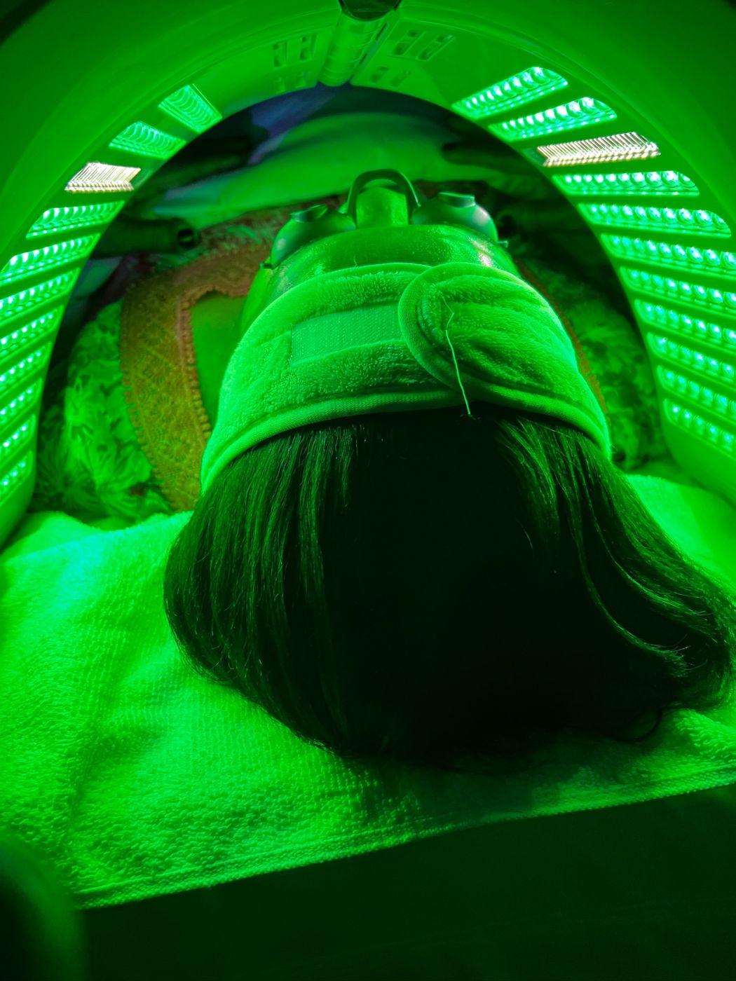 Client under a green LED light therapy dome