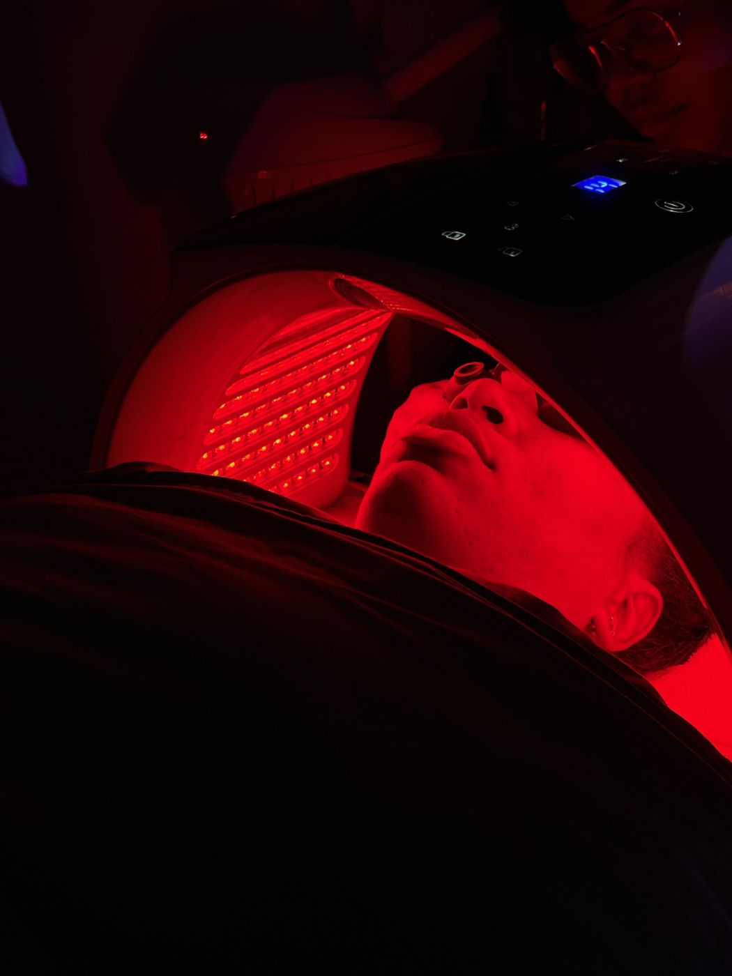 Client under a red LED light therapy dome